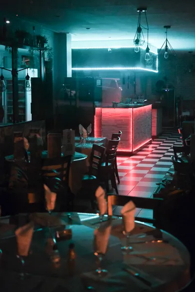 An empty restaurant, dimly lit by neon lights