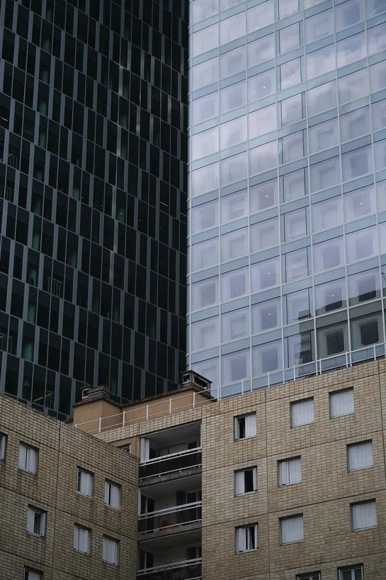 A somewhat large tenement building being largely overshadowed by a large skyscraper