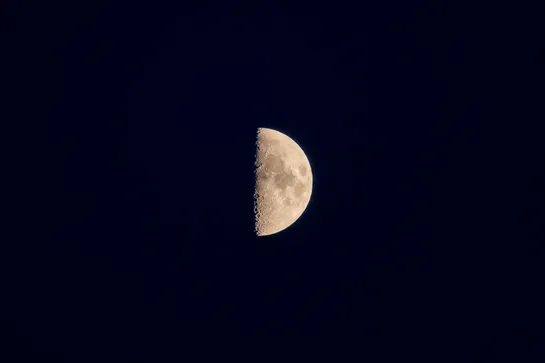 The moon, in its first quarter phase, in a black night sky