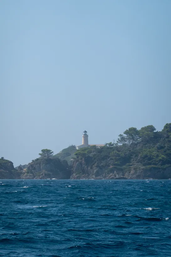A lighthouse atop a cliff, the sea below dark blue.