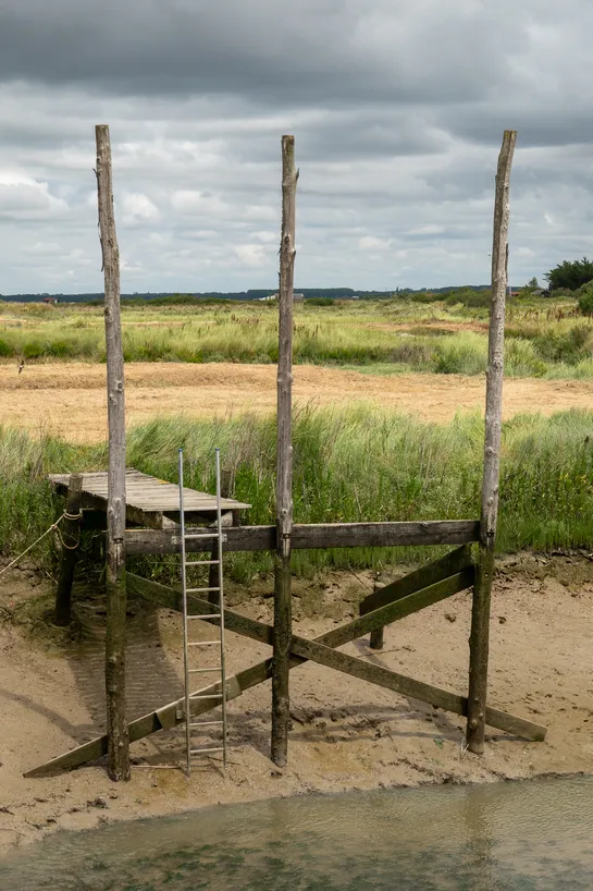 A wooden structure on the edge of a river with a low water level