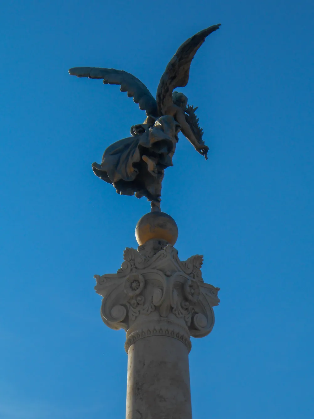 A statue of a winged figure on top of a stone column