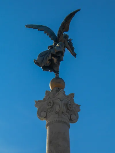 A statue of a winged figure on top of a stone column