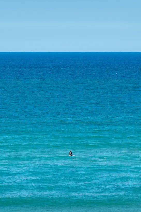 A lone surfer, gazing at the ocean, waiting for a wave
