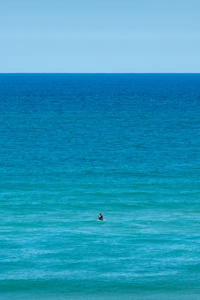 A lone surfer, gazing at the ocean, waiting for a wave