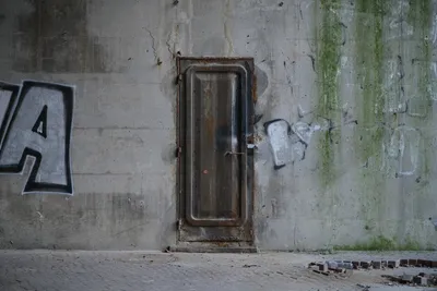 A concrete wall, in the center, a rusty metal door