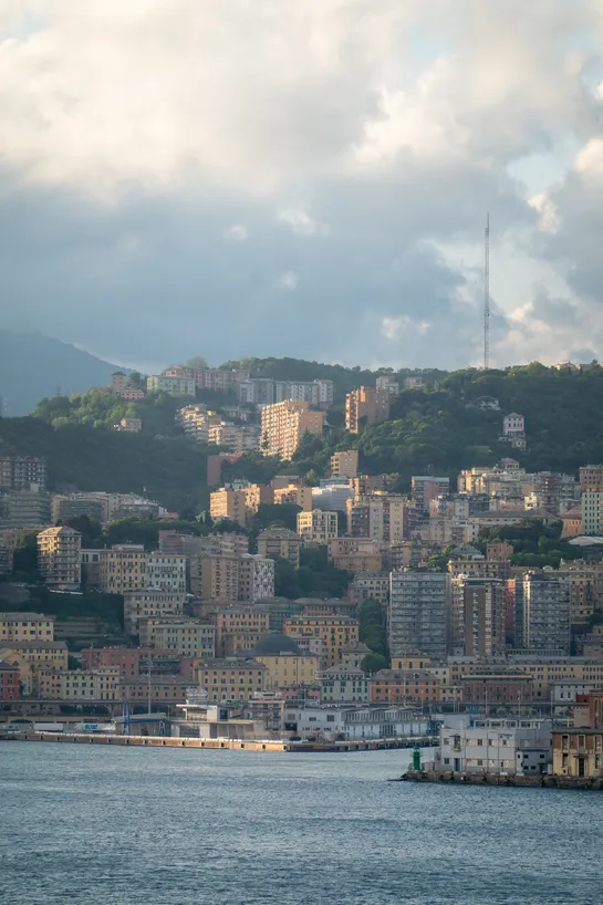 Buildings on the coast, the sea in the foreground, a large vertical metal mast in the background