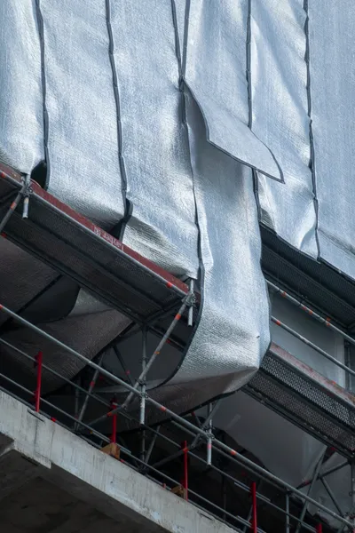 Silver sheets falling down the side of a building being built