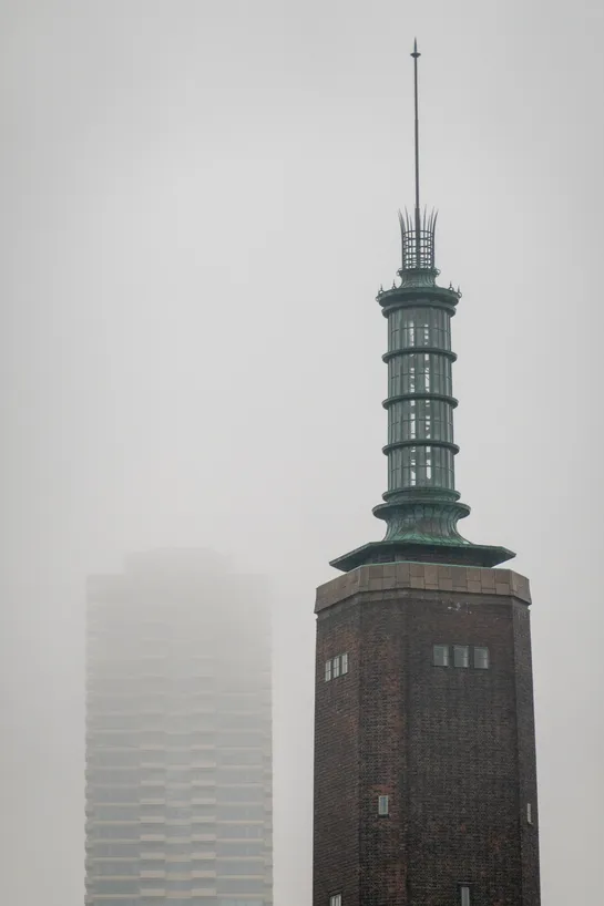 Two tall towers, a residential building on the left is farther and barely visible through the fog