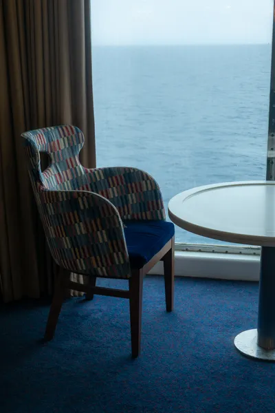 A fancy chair next to a window overlooking the sea