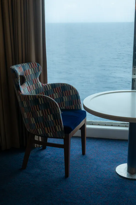 A fancy chair next to a window overlooking the sea