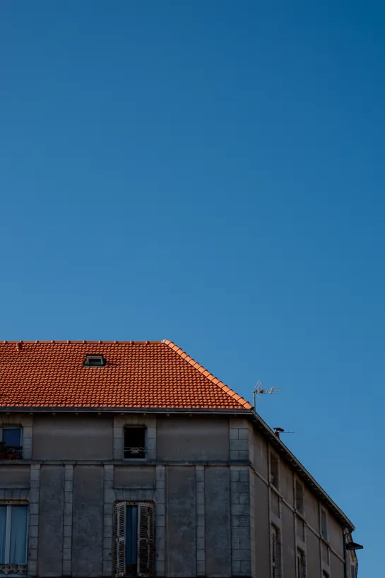 An old building, only its orange roof is lit by the sun