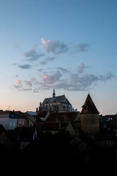Not much light on this city apart from the sky with small clouds dotting the center, a church sits directly beneath