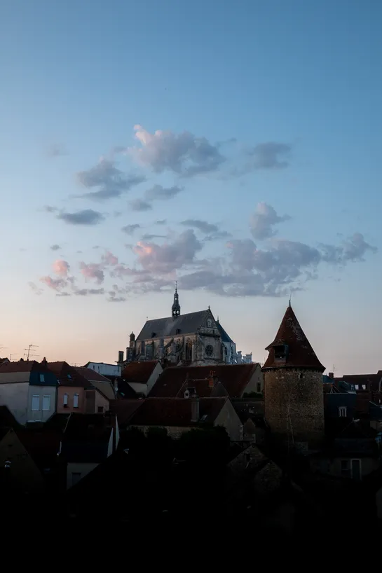 Not much light on this city apart from the sky with small clouds dotting the center, a church sits directly beneath
