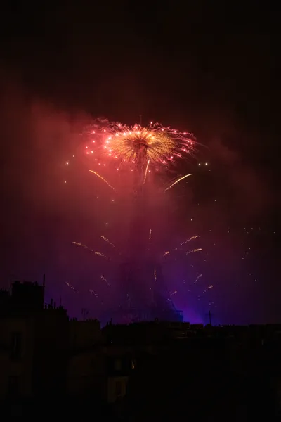 Fireworks fired from the top of the Eiffel Tower, the smoke is forming a gradient : red at the top, purple at the base