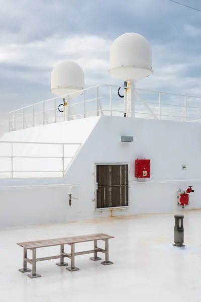 The top deck of a passenger boat, nearly everything white, two antenna radomes atop
