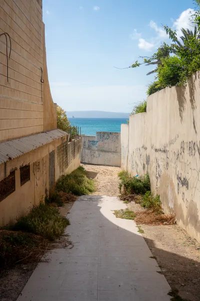 A path between buildings leads to the sea