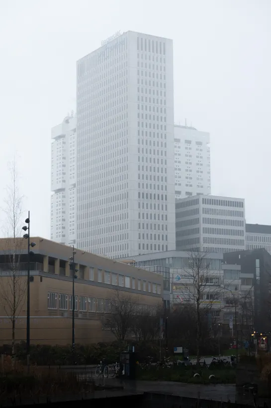 Tall white buildings appear above, despite the fog