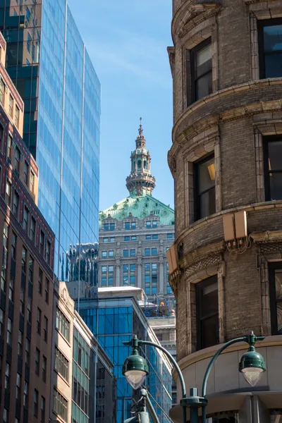 Through 2 layers of skyscrapers, we see the copper-stone spire of another skyscraper