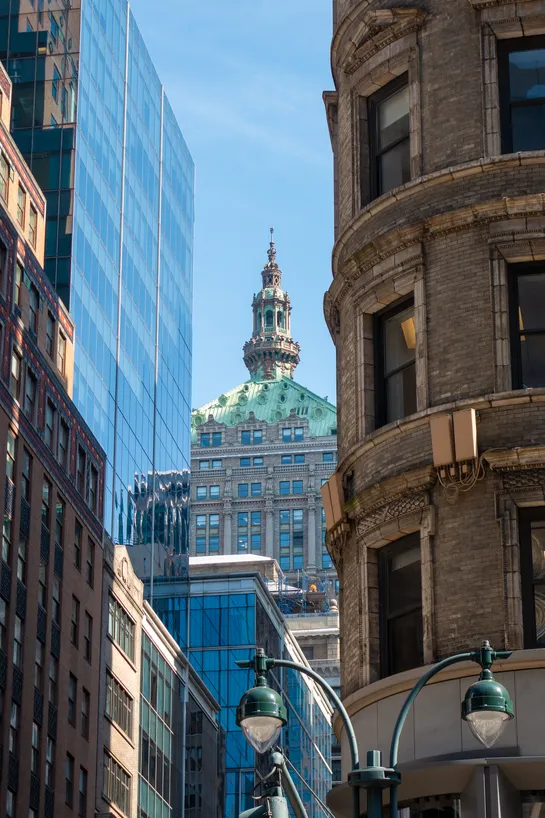 Through 2 layers of skyscrapers, we see the copper-stone spire of another skyscraper