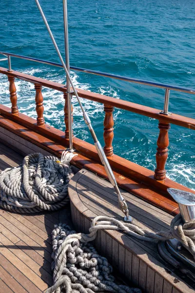 Ropes aboard a boat. Wooden railing and the sea behind.