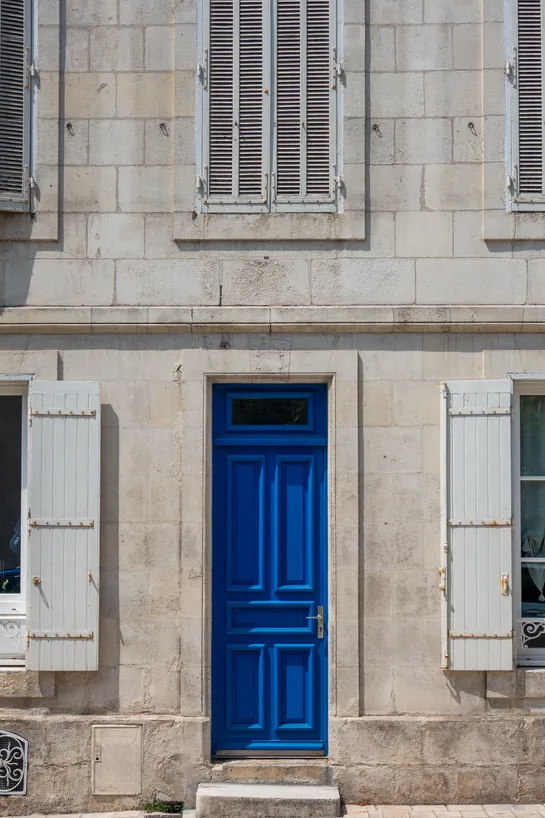 The very blue door of a plain stone building.