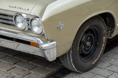 The front left of a muscle car, at an angle, both the headlights and tire are seen