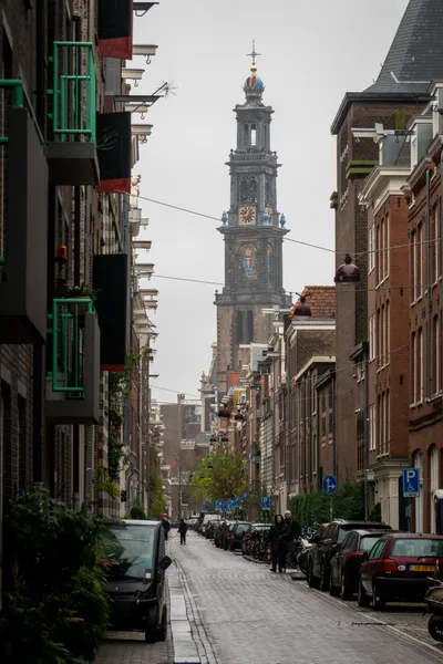 A church tower stands above residential brick buildings in a paved street