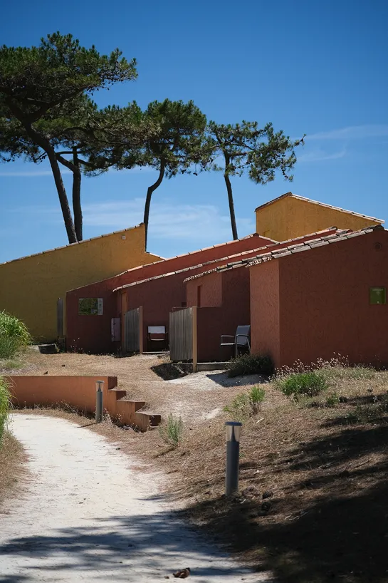 Ochre and yellow houses along a path, trees in the background