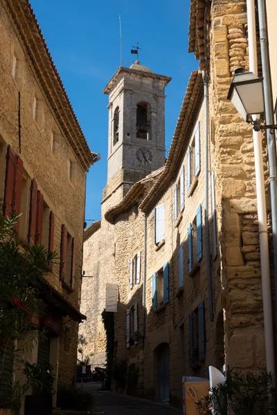 An older, brick church tower standing in the middle of a street with equally old residential buildings