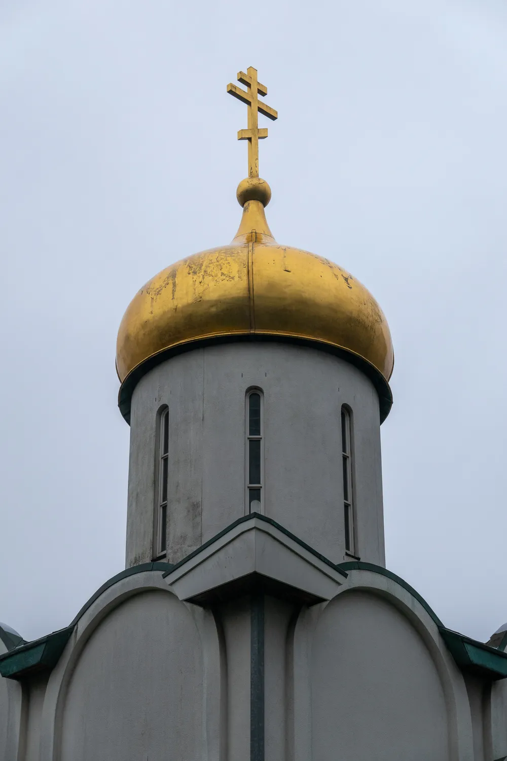 The tower of an orthodox church, its symbol and dome gilded above the otherwise white and plain building