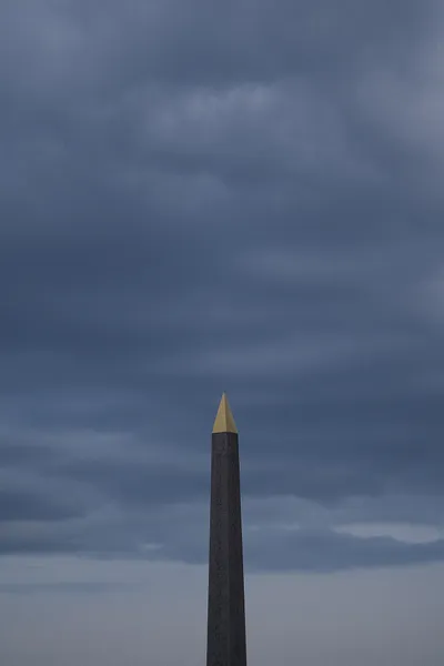 The Luxor Obelisk of the Place de la Concorde, barely lit beneath a cloudy sky