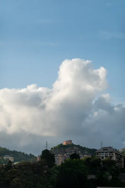 An orange building on top of a hill, a large cloud in the background